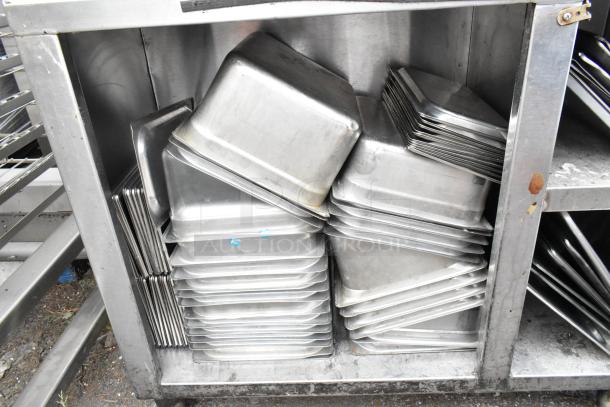 Stainless steel table with stacked drop-in bins and metal bowls, showing slight wear. Suitable for kitchen or industrial use.
