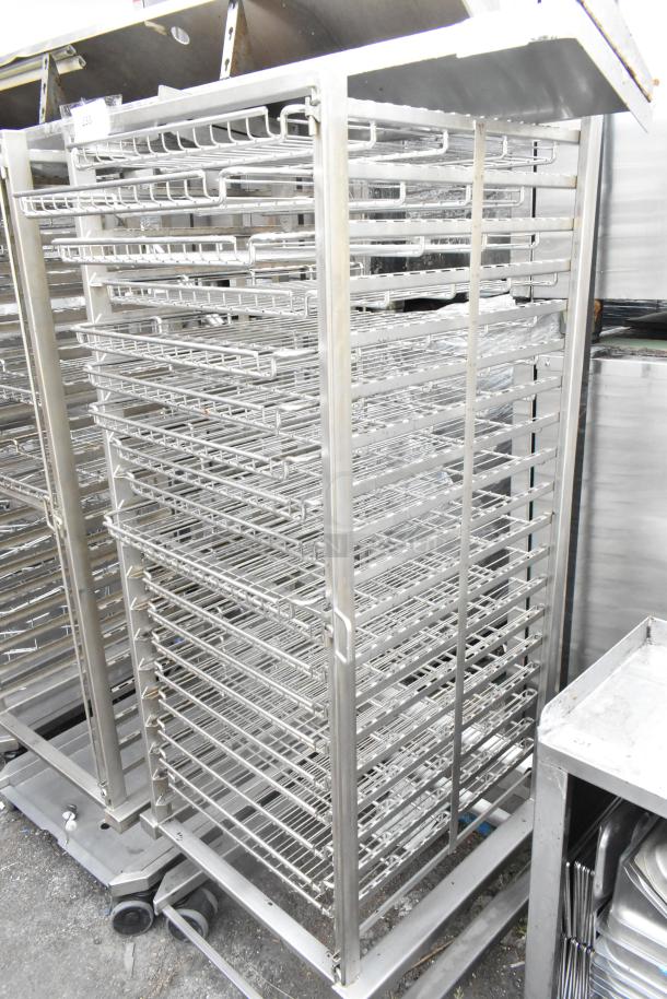 Metal pan transport rack with wire shelves and commercial casters, used condition. Ideal for kitchen storage and transport.