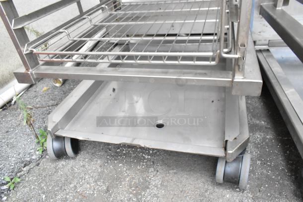 Metal commercial pan transport rack with wire shelves, featuring commercial casters. Slight wear visible.