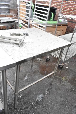 Stainless steel table with four legs, mounted on casters. Surface shows watermarks. Ideal for industrial or kitchen use.