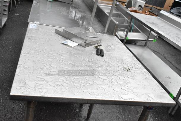 Stainless steel table with a smooth, water-beaded surface. Industrial design, durable condition, ideal for kitchen or workshop use.