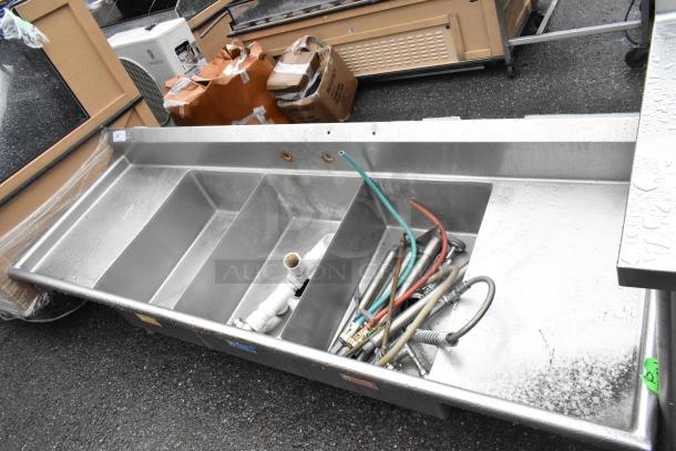 Stainless steel 3 bay sink with dual drain boards, no legs. Features plumbing accessories. Ideal for commercial use.