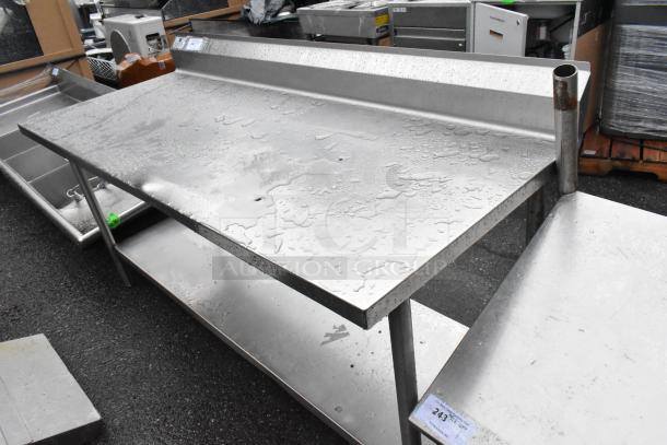 Stainless steel table with under shelf and back splash; visible water droplets; industrial-grade; good condition.