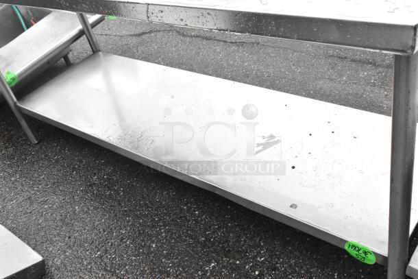 Stainless steel table with under shelf and back splash. Features sturdy construction, visible wear, and attached price tags.