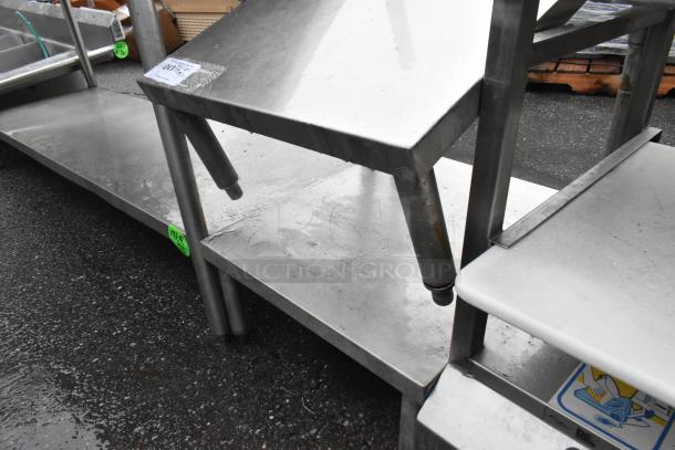 Metal 2-tier shelf with sturdy legs and flat surfaces. Appears in used condition with visible wear.
