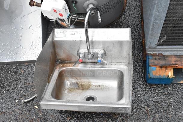 Stainless steel wall mount sink with faucet, handles, and side splash guards. Visible wear and rust, with auction tag 251.