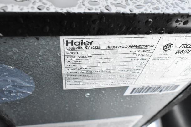 Haier HC27SW20RV mini cooler label, showing model, 115V, 1.3 amps, 2.7 cu. ft., cyclopentane insulation, under droplets.