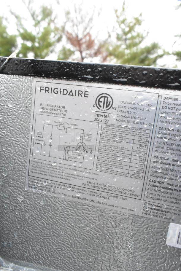 Frigidaire EFR749 label with specifications, model number, and certification details. Visible raindrops on textured surface.