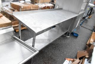 Stainless steel table with under shelf, used condition, visible watermarks, and slight surface wear, suitable for kitchen use.
