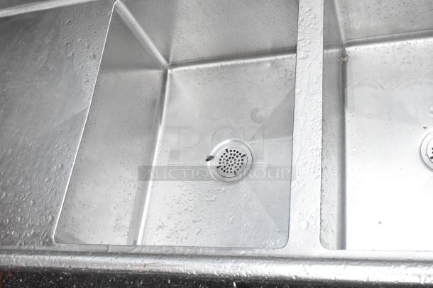 Stainless steel 3 bay sink with dual drain boards, no legs. Used condition, visible water stains.