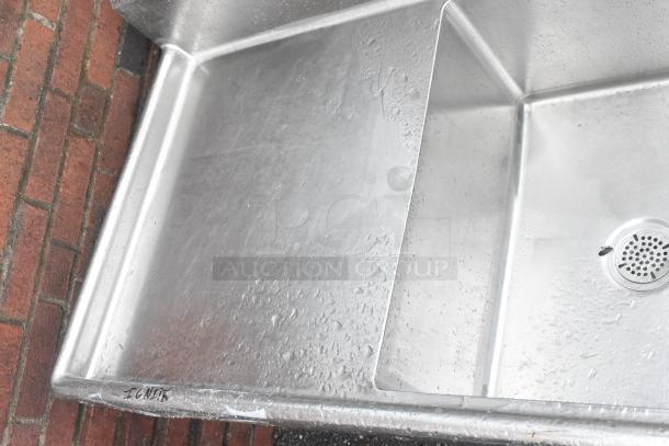Stainless steel 3 bay sink with dual drain boards. No legs. Good condition, visible water spots.