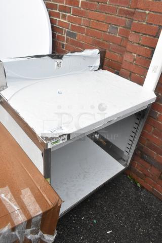 Brand new Regency 600EBTB2436 stainless steel table, 24"x36", with adjustable midshelf and 6" backsplash, visible scratches.