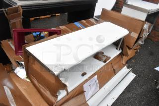 Stack of damaged boxes containing assorted items, including a Lancaster Table & Seating Alloy Blue Quartz Outdoor Arm Chair, marked "scratch and dent."