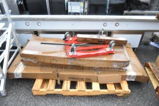 Four brand new scratch and dent items on wooden pallet, including red dolly, Regency equipment stand, and Lavex dispenser.