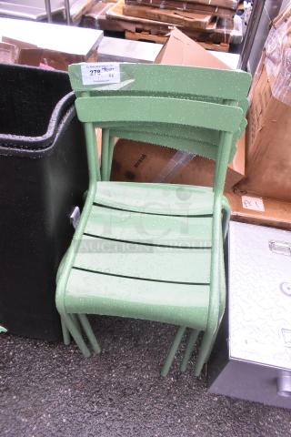 Three green patio chairs, brand new with minor scratches, stacked outdoors. Includes auction tag indicating lot quantity.