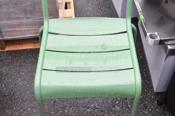 Green patio chair with raindrops, showing metal slatted seat, minor scratches visible. New, part of a set of three.