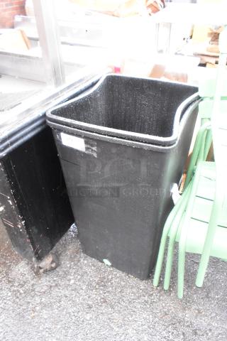 Brand new black poly trash bin, slight scratches, visible label with "275," durable design, set of two bins.