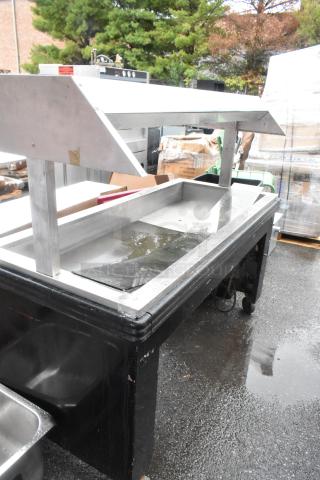 Metal commercial heated buffet station with overhead warmer, stainless steel construction, and visible wear.