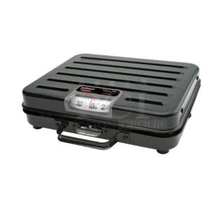 Brand new Rubbermaid Pelouze 250 lb. mechanical shipping scale, model FGP250S, black briefcase style, on legs.