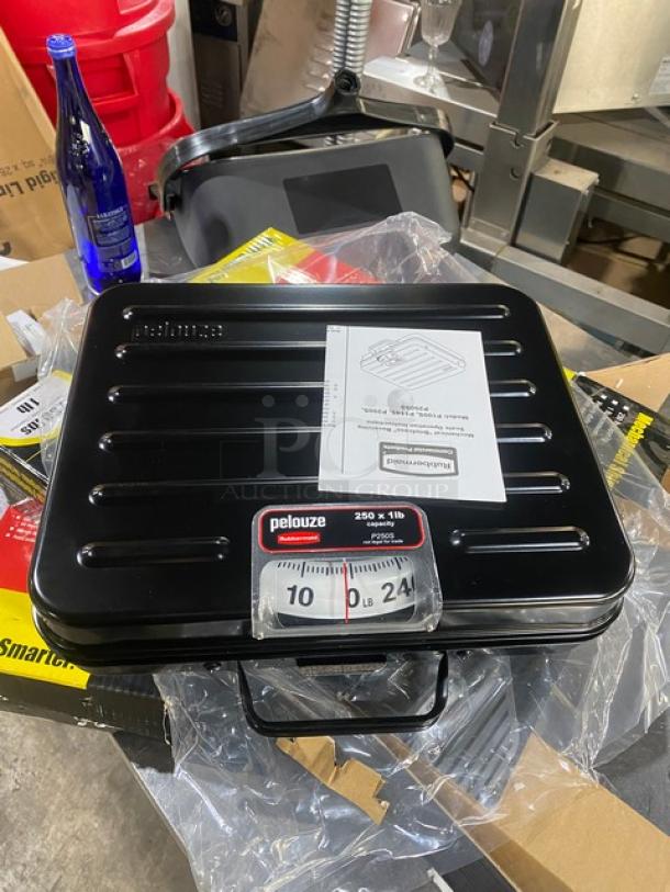 Brand new Rubbermaid Pelouze FGP250S mechanical scale, 250 lb. capacity, black briefcase-style, visible manual, on legs.