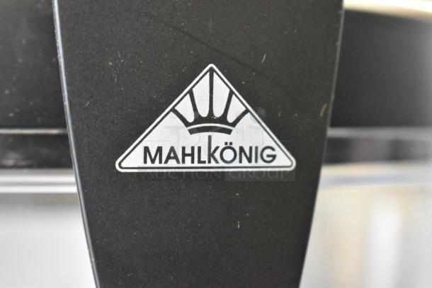 "Brand new Mahlkonig E65W espresso grinder, black, 2.6 lb. capacity, 110-127V, 1 Phase, with minor scratches. Logo visible."