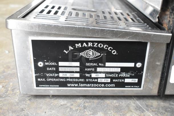 La Marzocco N/21 2 AV stainless steel espresso machine label, voltage 208-240, single phase, model and serial number visible.