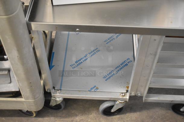 Dutchess DoughXpress DMS-18 NH dough press on metal pan rack with commercial casters, protective film visible, minor wear.
