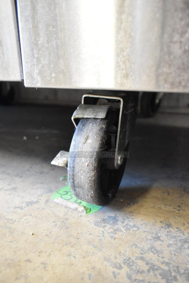 Cook Rite commercial gas range caster, showing sturdy black wheel and metal mount, slightly worn, on concrete floor.