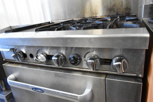 Cook Rite stainless steel 4 burner range with flat top griddle, oven, overshelf, and backsplash. Gas-powered on commercial casters.