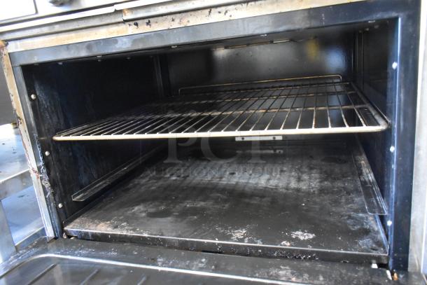 Cook Rite gas range oven interior, showing metal shelf and signs of use, part of commercial 4 burner range with griddle.