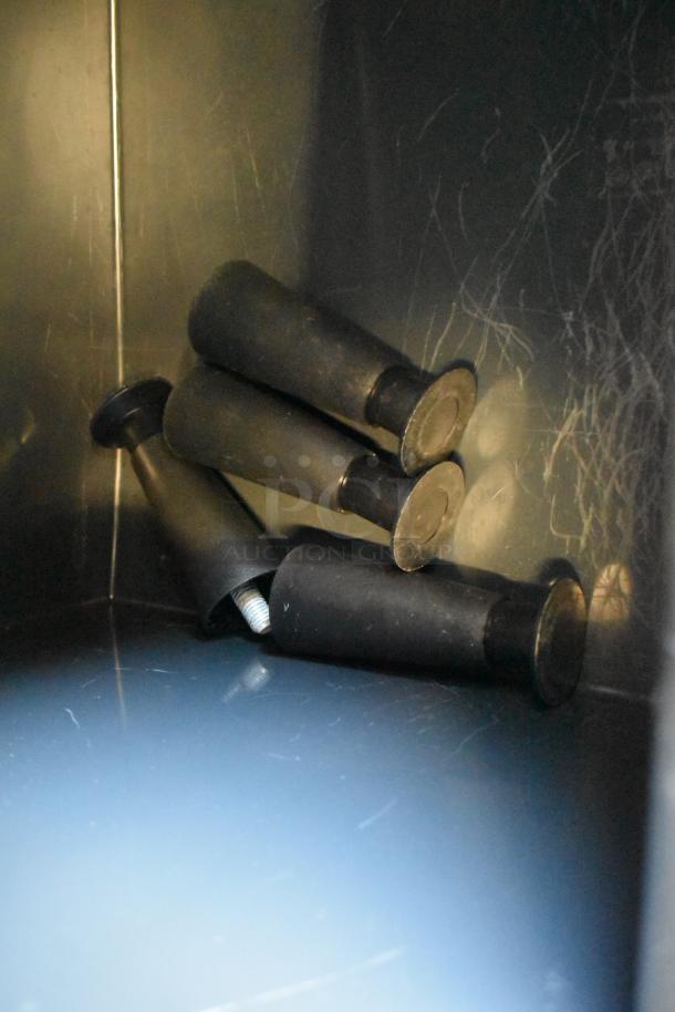 Black rubber feet for a Scotsman UC2024MA-1A undercounter ice machine, placed within a scratched metal compartment.
