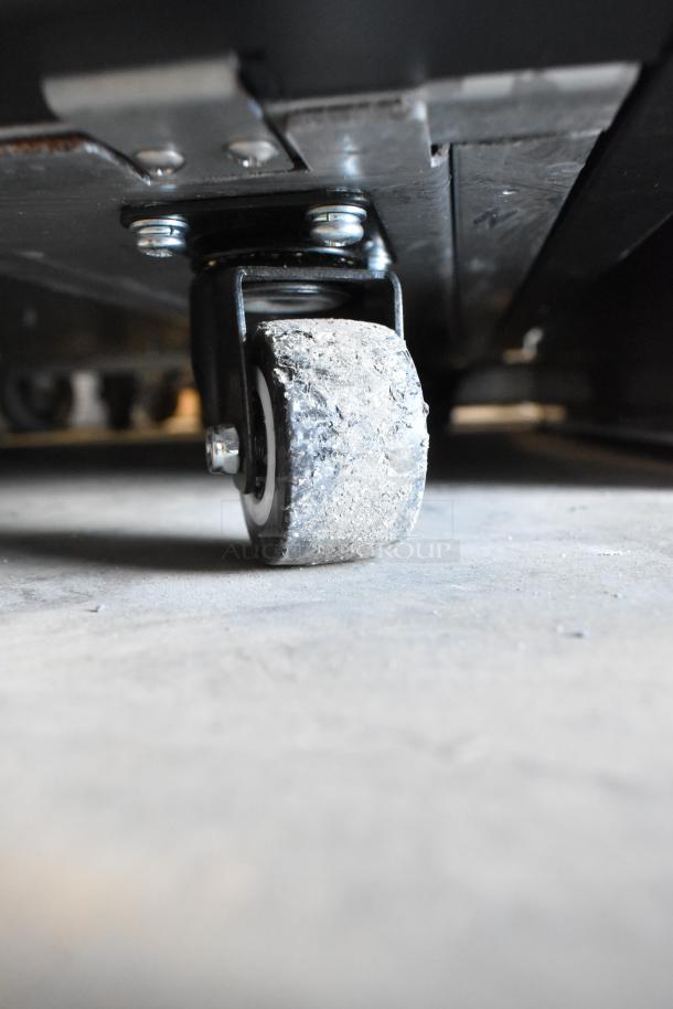 Close-up of a heavy-duty commercial caster on the Avantco 193VOA36B merchandiser, highlighting rugged, slightly worn wheel.