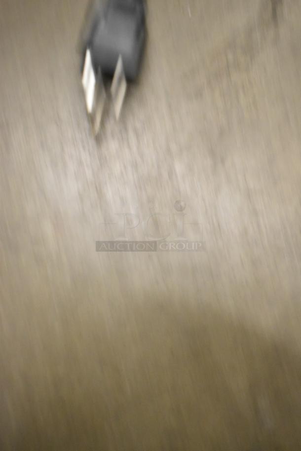Blurred image of a power plug on a surface. The item is not clearly visible.