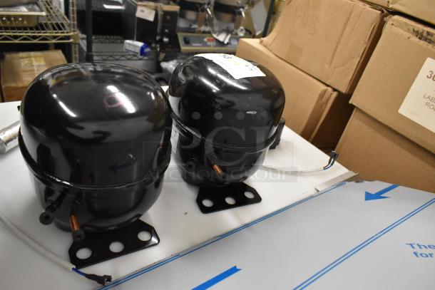 Two new Cubigel compressors, models NUT55NR and NUT70NR, 115-127V, scratch and dent condition.