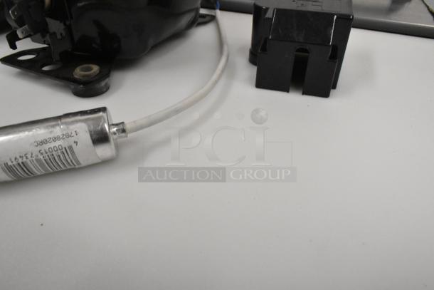 Brand new Cubigel NUT55NR and NUT70NR compressors, 115-127V, 1 phase; minor scratches, with visible labels and attached components.