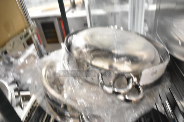 Nine brand new metal kitchen items, including pots and a whisk, with scratch and dent condition. Wrapped in plastic.