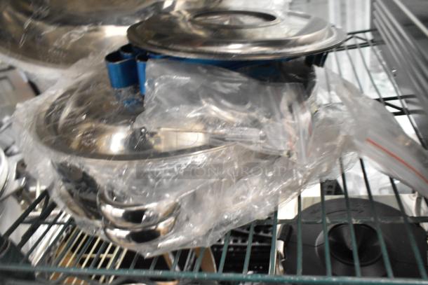 Nine brand new scratch and dent items, including a metal whisk and metal pots, wrapped in plastic, on a metal shelf.