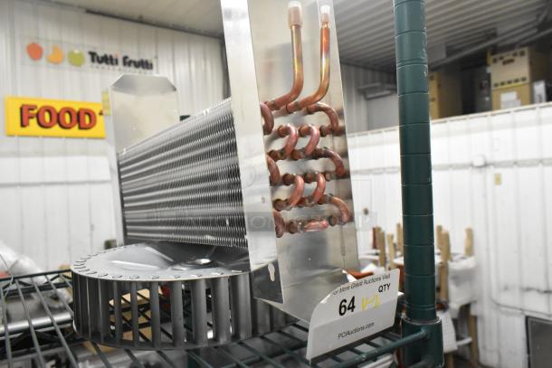 Brand new evaporator coil and blower piece with visible copper tubing and metallic fins. Auction item tag: 64, qty V-2.