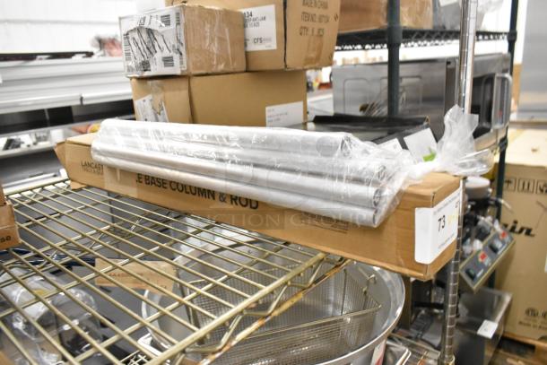 Two new Lancaster Table & Seating 164TCOLROD25 table base columns and rods in original packaging, on storage shelf.