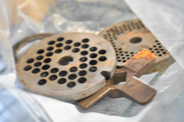 Close-up of metal components with circular holes and rust spots, possibly parts for industrial equipment.