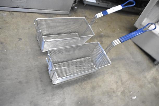 Two brand new metal fry baskets with blue handles, scratch and dent condition, on industrial floor.