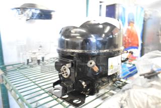 BRAND NEW SCRATCH AND DENT Cubigel NUG80NR 17818171C Compressor, black, visible wiring, on display shelf.