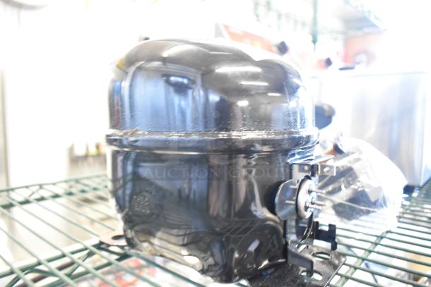 BRAND NEW Cubigel NUG80NR 17818171C compressor on a metal shelf, shiny black finish, minor scratches visible.
