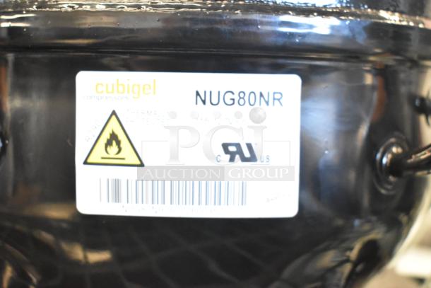 Brand new Cubigel NUG80NR compressor, visible scratch and dent. Label shows model, fire hazard symbol, barcode.