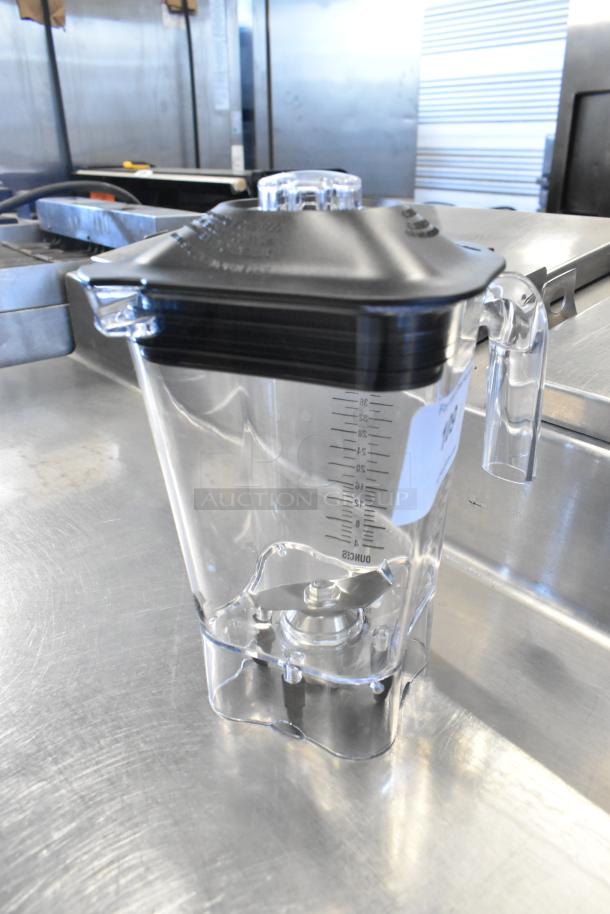 Brand new scratch and dent clear poly blender pitcher with measuring marks, black lid, and durable handle.