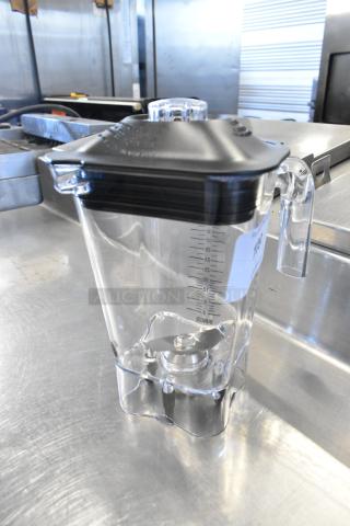 Brand new scratch and dent clear poly blender pitcher with measuring marks, black lid, and durable handle.
