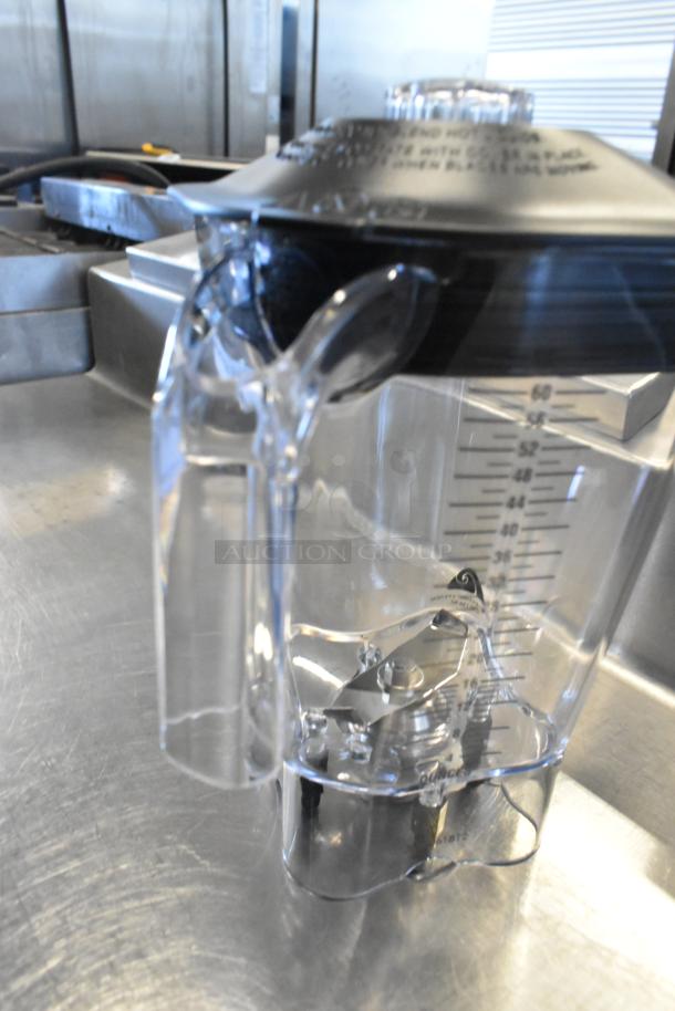 Clear poly blender pitcher, new with scratch and dent. Marked with measurement indicators. Black lid with caution labels.