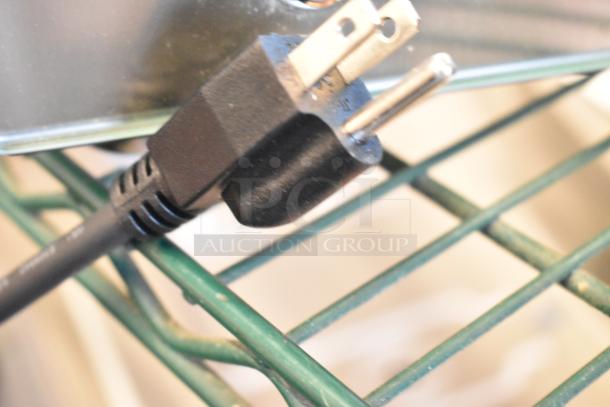 Black electrical plug on a metal shelf, part of a Carnival King 382HDSG2A hot food display case, 120 volts, 1 phase.