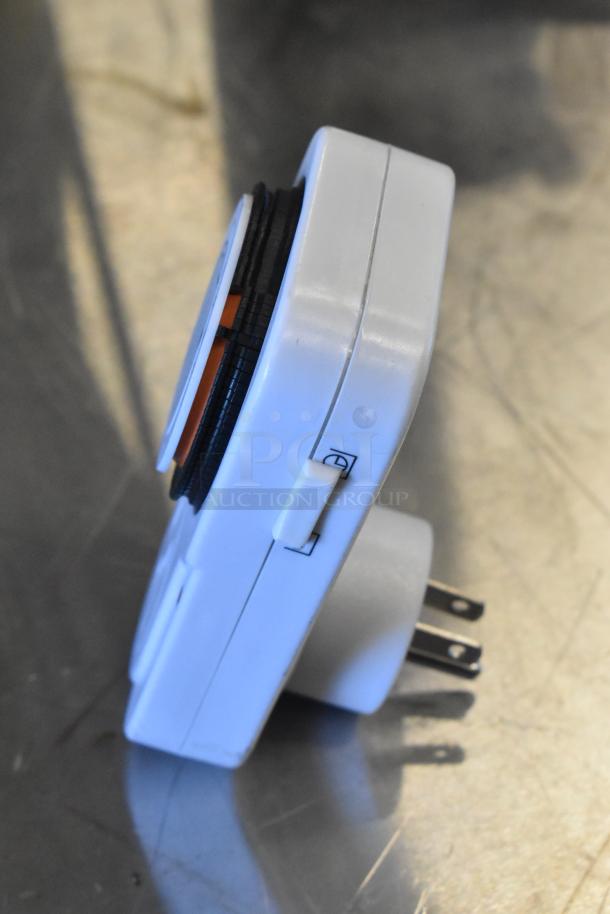 Tanda TS-MU3 grounded outlet timer, white, features adjustable dial and switch. Good condition, shown on metallic surface.