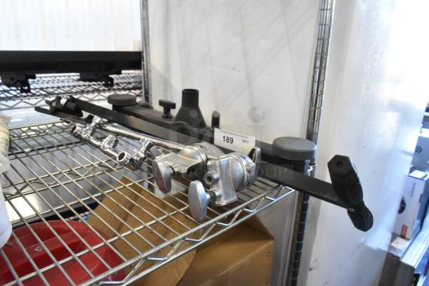 Four faucet handles and pieces on a metal shelf. Chrome finish, used condition. Includes black and silver components. Auction tag 189 visible.